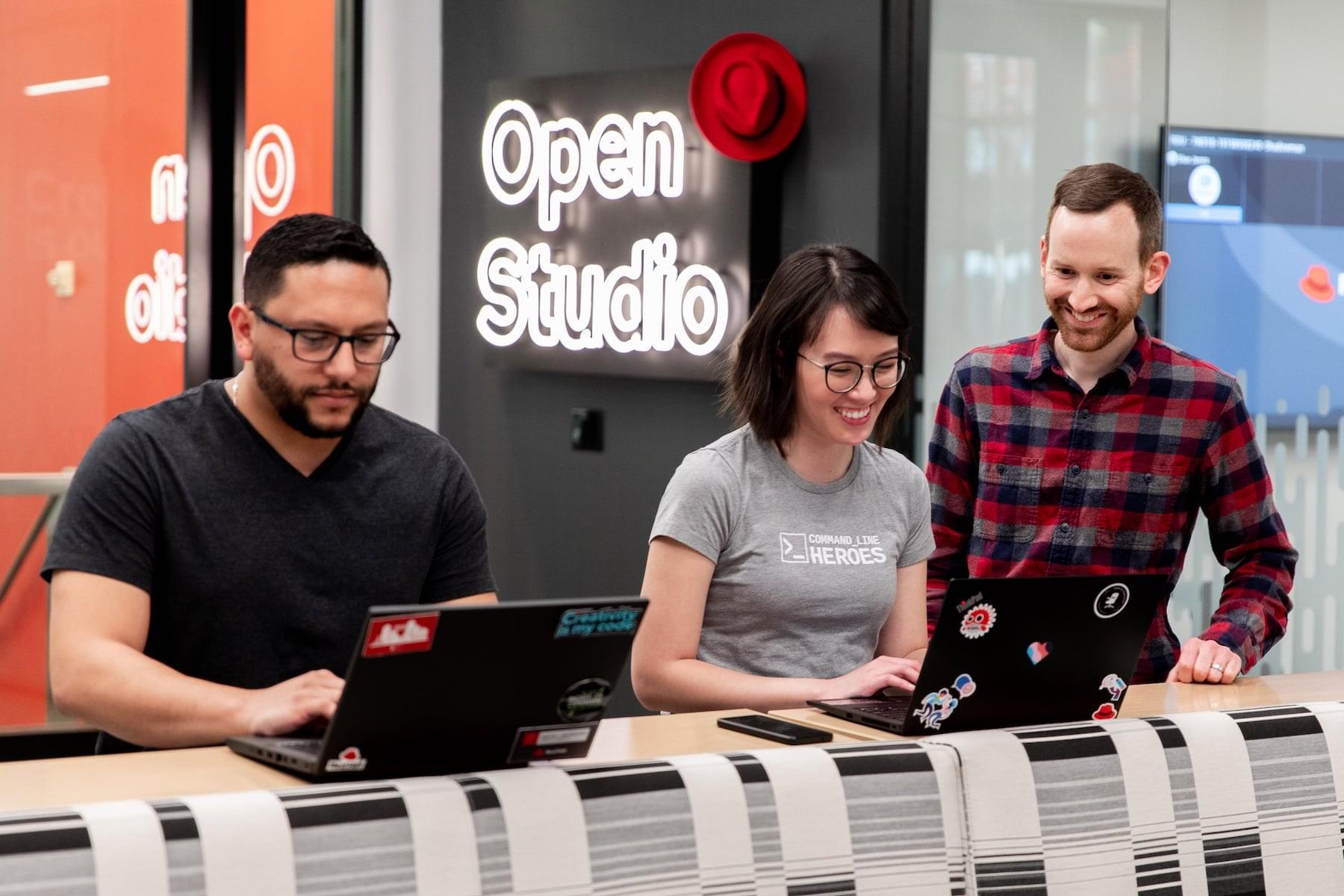 Three people looking at laptops and working together in a Red Hat Open Studio room