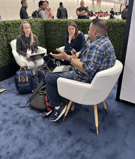 Three Red Hat Summit participants sitting in chairs having a conversation