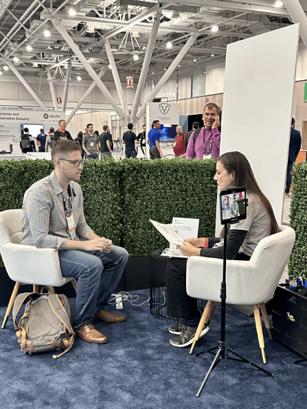 Two Red Hat Summit participants sitting in chairs talking with each other