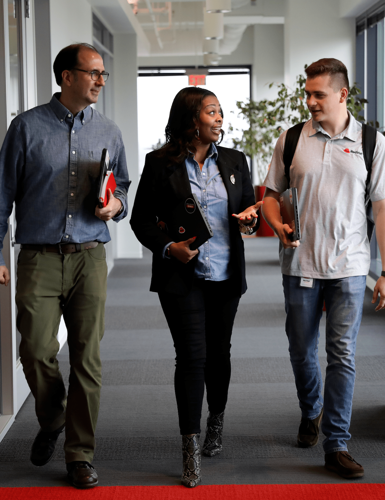 Three people walking and talking in a hallway